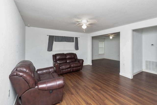 living room with ceiling fan, dark wood-type flooring, and a textured ceiling