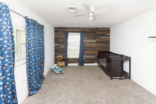 interior space featuring ceiling fan, carpet flooring, a wealth of natural light, and wooden walls