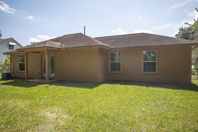 back of house with central AC unit and a lawn