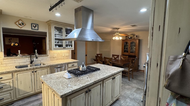 kitchen featuring island exhaust hood, appliances with stainless steel finishes, decorative backsplash, a kitchen island, and sink