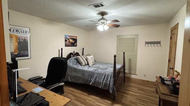 bedroom with ceiling fan, hardwood / wood-style floors, and a textured ceiling