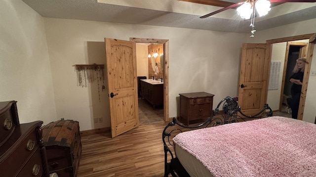 bedroom featuring ceiling fan, light wood-type flooring, connected bathroom, and a textured ceiling