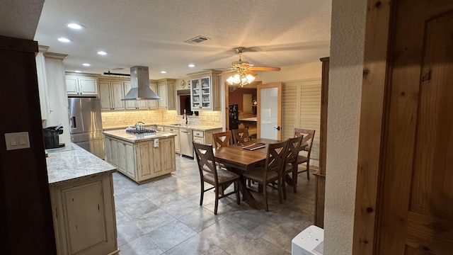 kitchen featuring appliances with stainless steel finishes, a kitchen island, island exhaust hood, tasteful backsplash, and sink