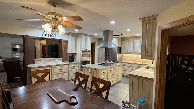 kitchen with island range hood, tasteful backsplash, cream cabinets, and a center island