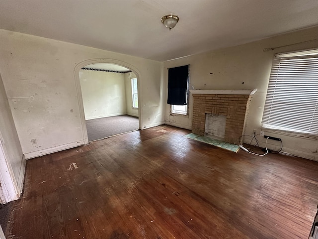 unfurnished living room featuring dark hardwood / wood-style floors and a brick fireplace