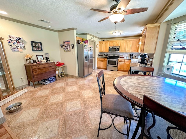 kitchen featuring ceiling fan, crown molding, stainless steel appliances, and a textured ceiling