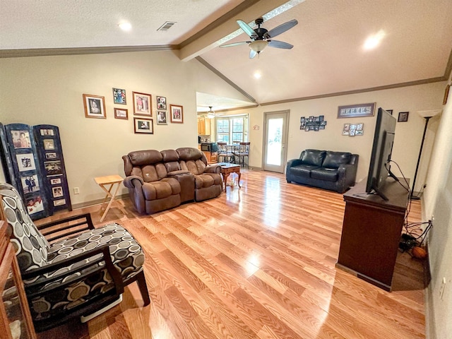 living room with light wood-type flooring, ornamental molding, a textured ceiling, ceiling fan, and vaulted ceiling with beams