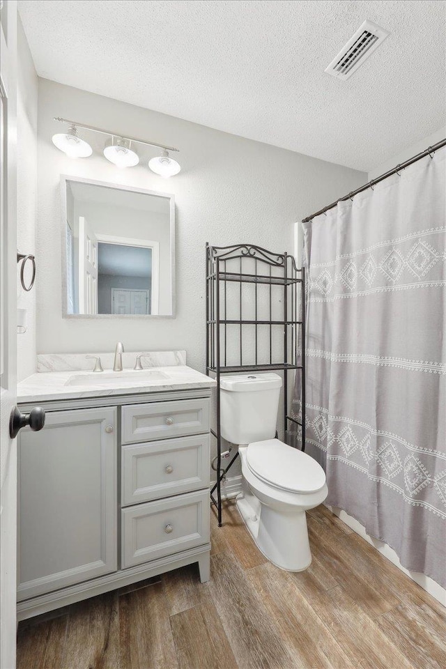 1663 Bluebonnet St, Vidor, TX 77662 - full bathroom with wood finished floors, vanity, a textured ceiling, toilet, and a shower with shower curtain