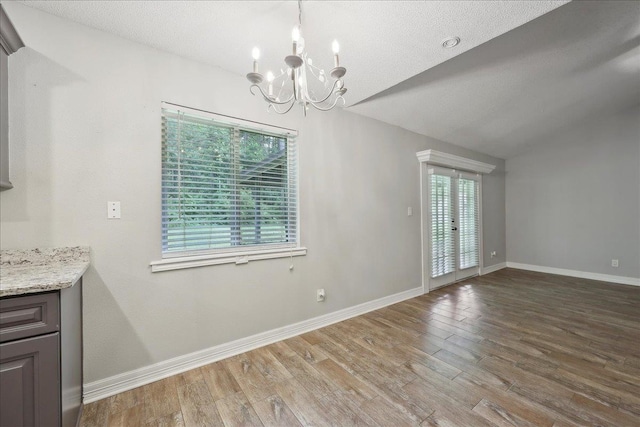 1663 Bluebonnet St, Vidor, TX 77662 - unfurnished dining area with a chandelier, wood finished floors, baseboards, and lofted ceiling