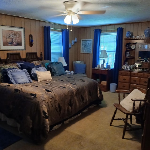 bedroom with multiple windows, light carpet, wood walls, and a textured ceiling