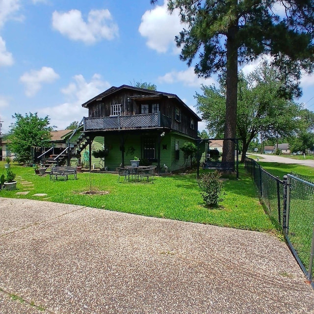 rear view of house with stairs, a lawn, fence, and a wooden deck