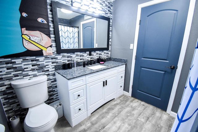 bathroom featuring backsplash, vanity, wood-type flooring, and toilet