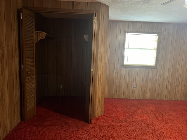 hallway featuring carpet flooring and wood walls