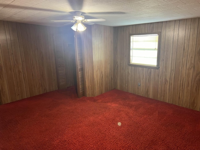 empty room featuring carpet flooring, ceiling fan, and wood walls