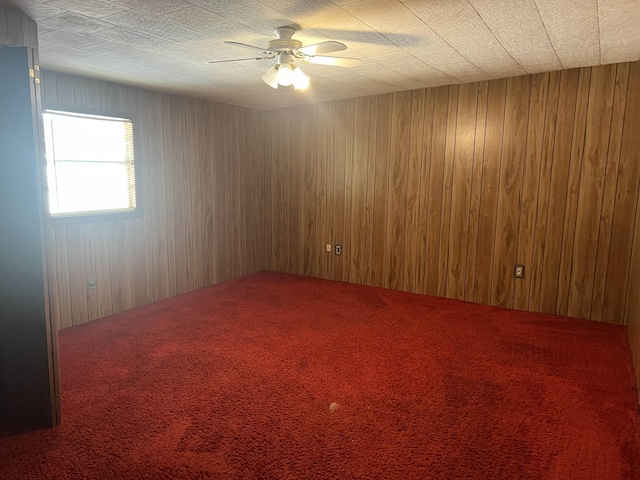 unfurnished room featuring carpet, ceiling fan, and wooden walls