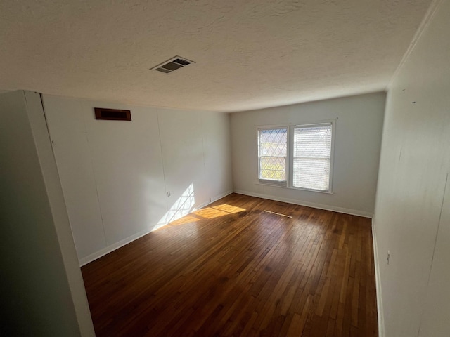 empty room with a textured ceiling and dark hardwood / wood-style floors