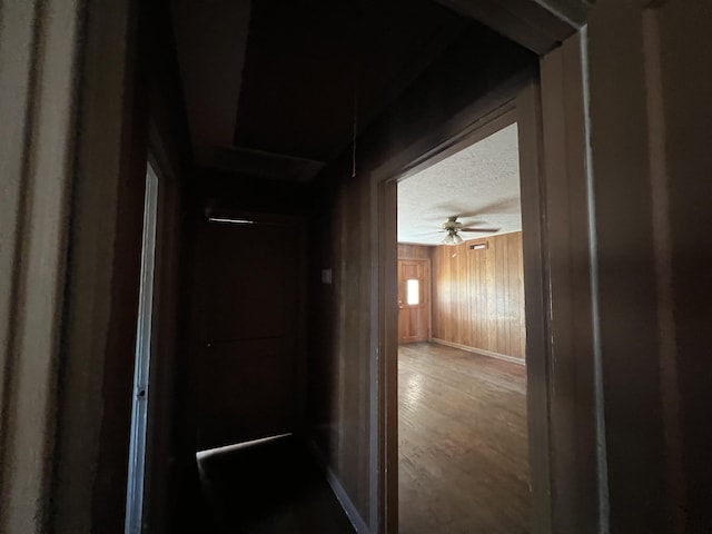 hallway with wood walls and a textured ceiling