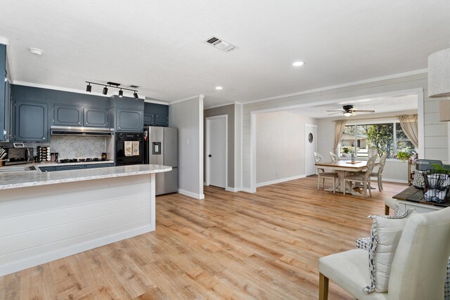 kitchen with light wood-style floors, tasteful backsplash, visible vents, and stainless steel fridge