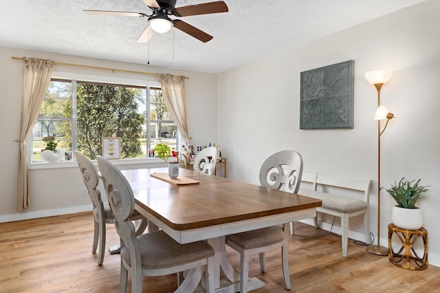 dining space featuring baseboards, a textured ceiling, light wood-style floors, and a ceiling fan