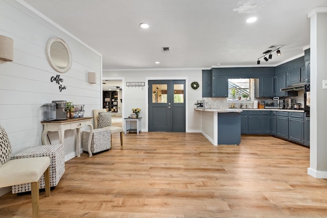 kitchen featuring light wood-type flooring, visible vents, blue cabinetry, light countertops, and decorative backsplash