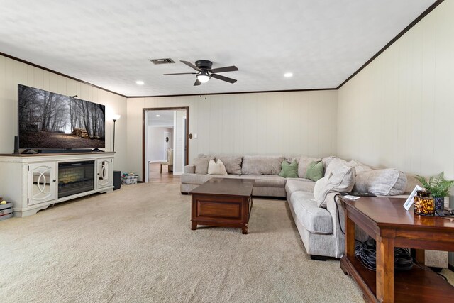 living room with ceiling fan, light carpet, visible vents, and ornamental molding