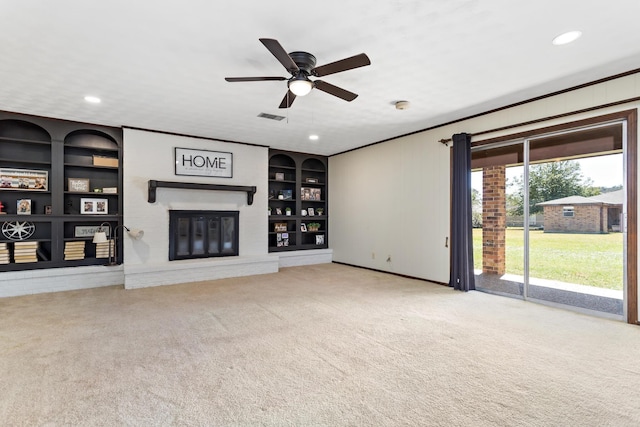 unfurnished living room with visible vents, ornamental molding, built in features, a glass covered fireplace, and carpet floors