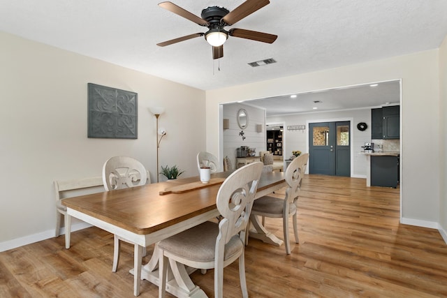 dining area featuring visible vents, a ceiling fan, a textured ceiling, light wood-style floors, and baseboards