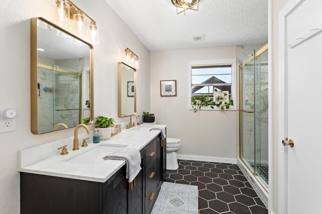 bathroom featuring a sink, a textured ceiling, a stall shower, and toilet