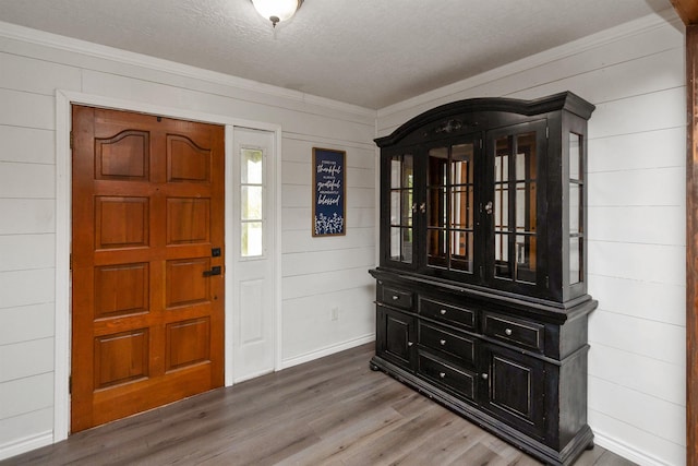 foyer entrance with hardwood / wood-style floors, a textured ceiling, and wooden walls