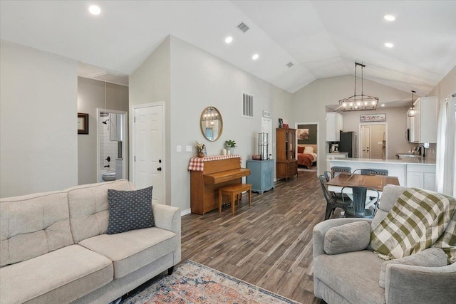 living room with a chandelier, wood-type flooring, and vaulted ceiling