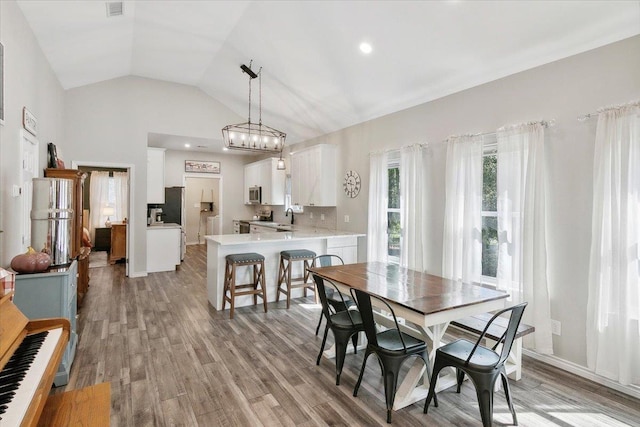 dining room with light hardwood / wood-style floors, vaulted ceiling, and sink