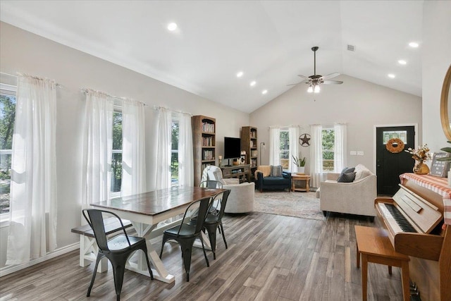 dining room with ceiling fan, plenty of natural light, high vaulted ceiling, and hardwood / wood-style flooring