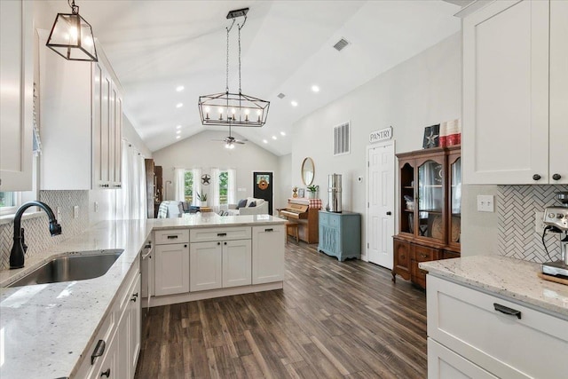 kitchen with pendant lighting, lofted ceiling, white cabinets, sink, and ceiling fan