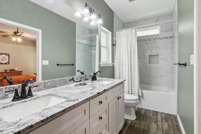 full bathroom featuring hardwood / wood-style floors, vanity, ceiling fan, toilet, and shower / bathtub combination with curtain