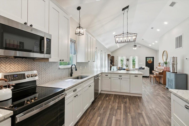 kitchen with sink, kitchen peninsula, decorative light fixtures, lofted ceiling, and appliances with stainless steel finishes