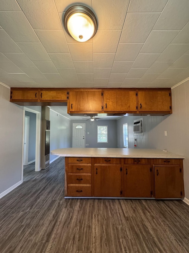 kitchen with ceiling fan, kitchen peninsula, dark wood-type flooring, and an AC wall unit