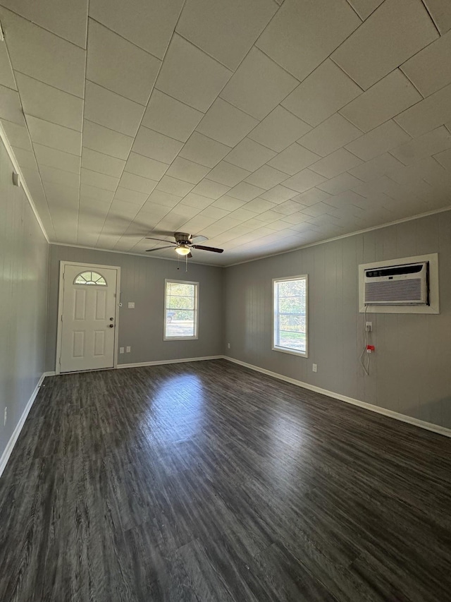 unfurnished living room featuring a wall mounted air conditioner, dark hardwood / wood-style floors, ceiling fan, and ornamental molding