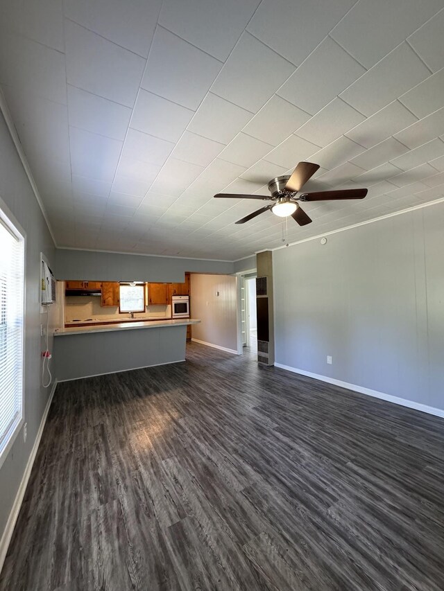 unfurnished living room featuring ceiling fan, crown molding, and dark wood-type flooring