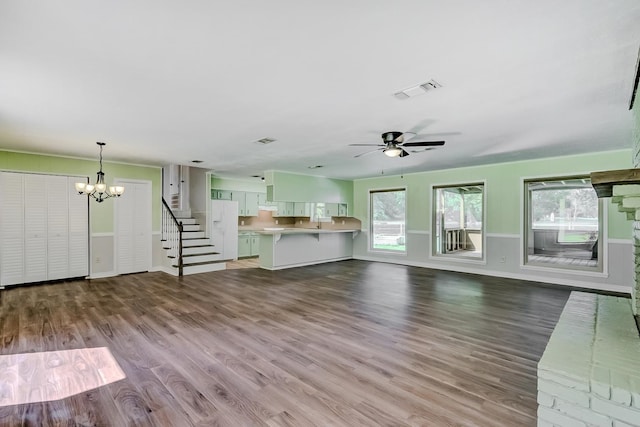 unfurnished living room featuring hardwood / wood-style floors, ceiling fan with notable chandelier, and sink