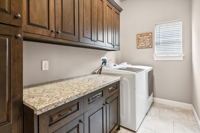 washroom featuring separate washer and dryer, light tile patterned floors, and cabinets