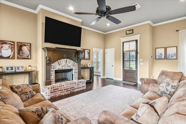 living room featuring ceiling fan, dark hardwood / wood-style flooring, ornamental molding, and a brick fireplace