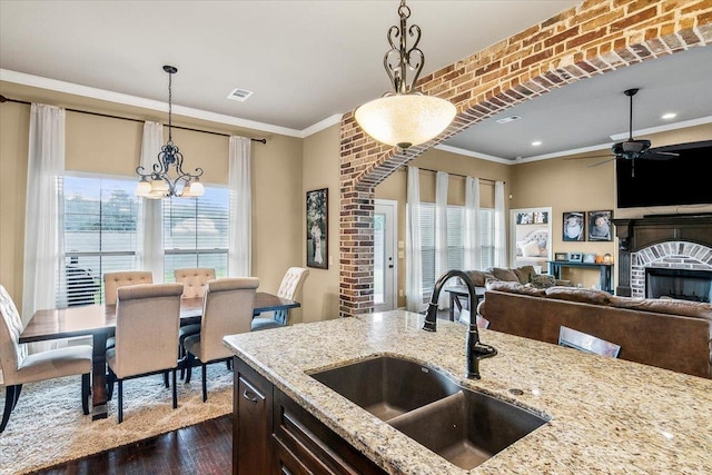 kitchen featuring decorative light fixtures, light stone counters, ornamental molding, and sink