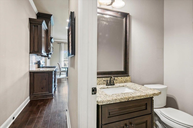 bathroom with decorative backsplash, ornamental molding, vanity, hardwood / wood-style floors, and toilet