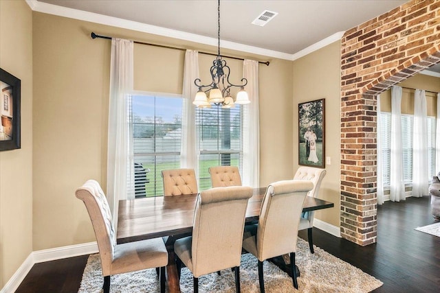 dining space with crown molding, dark hardwood / wood-style flooring, a healthy amount of sunlight, and an inviting chandelier