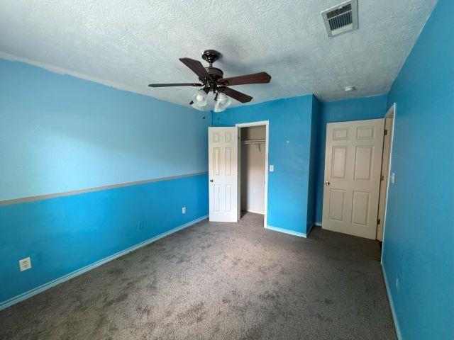 2985 Willow Pl, Beaumont, TX 77707 - unfurnished bedroom with a textured ceiling, a closet, carpet floors, and a ceiling fan