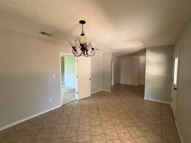 2985 Willow Pl, Beaumont, TX 77707 - unfurnished room featuring a chandelier, a textured ceiling, and light tile patterned floors