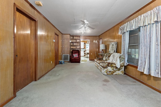 carpeted living room with wooden walls and ceiling fan