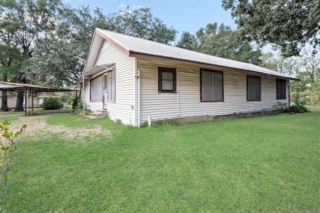 view of side of home featuring a yard, metal roof, and entry steps