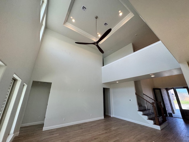 unfurnished living room with visible vents, baseboards, dark wood finished floors, a high ceiling, and stairs