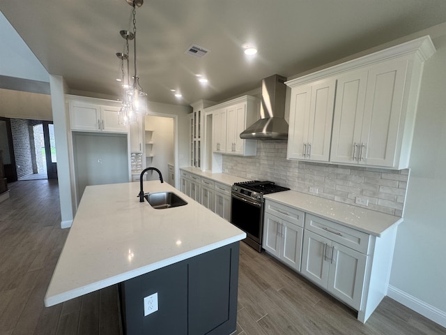 14865 Norma Jane Ln, Beaumont, TX 77713 - kitchen with stainless steel gas range, a sink, wall chimney exhaust hood, white cabinetry, and decorative backsplash